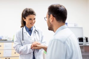 Young female doctor hold hand of caucasian man patient give comfort, express health care sympathy, medical help trust support encourage reassure infertile patient at medical visit